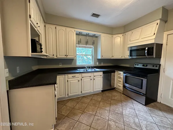 a kitchen with stainless steel appliances granite countertop a stove a sink and a microwave