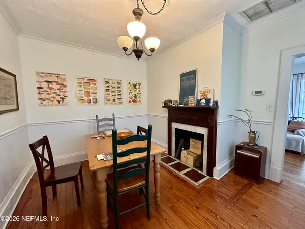 a view of a dining room with furniture wooden floor fireplace and a chandelier