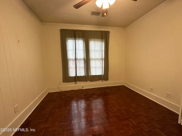 an empty room with wooden floor and windows
