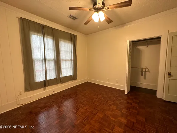 a view of an empty room with a window and wooden floor