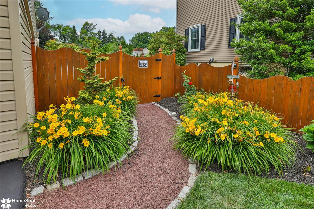 2821 Center Street Bethlehem, PA 18017 - Photo 59 of 68 A charming wooden fence encloses a path lined with vibrant yellow daylilies, leading to a private entrance.