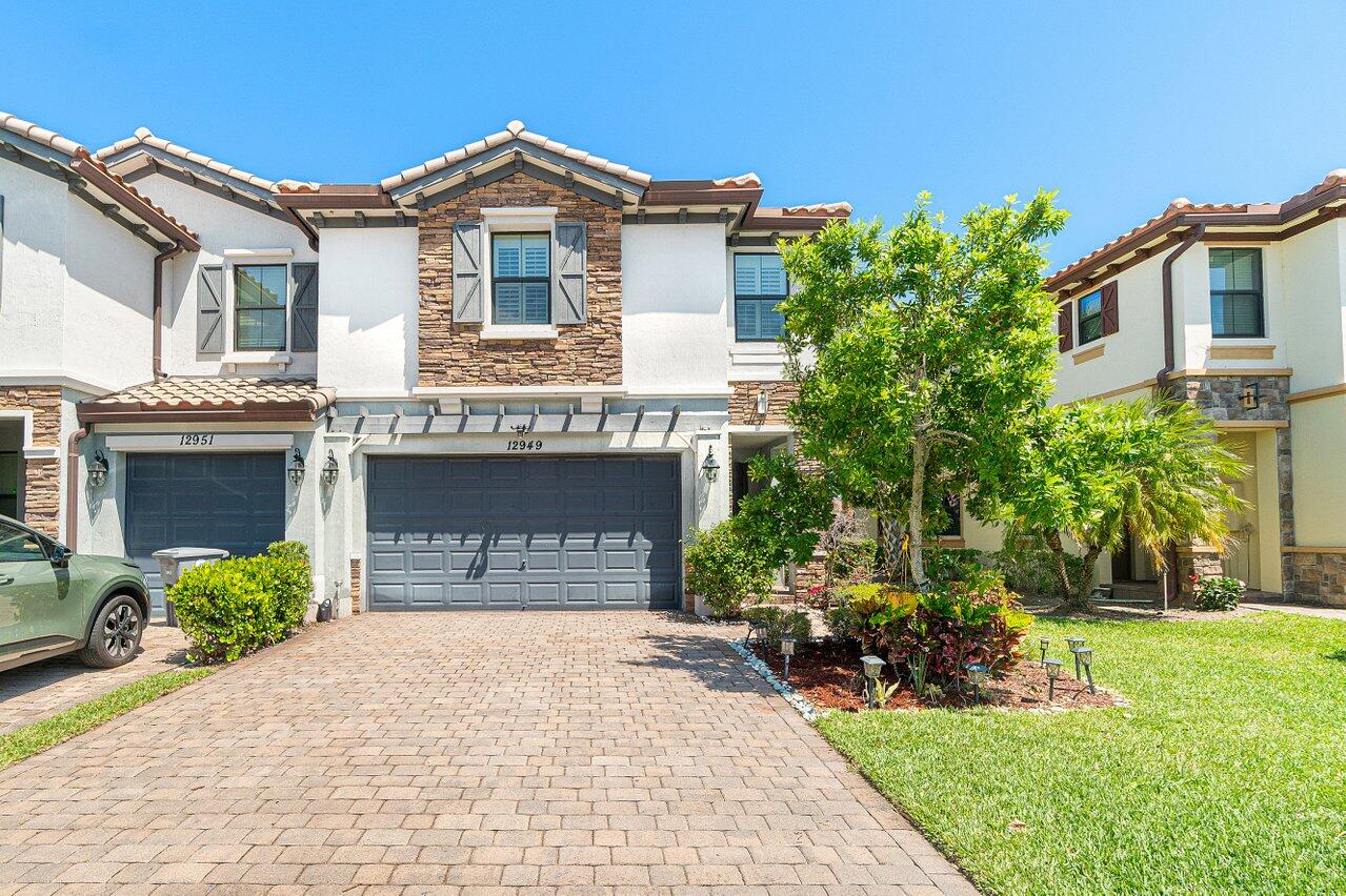 12949 Anthorne Lane Boynton Beach, FL 33436 - Photo 1 of 37 a front view of a house with a garden and plants