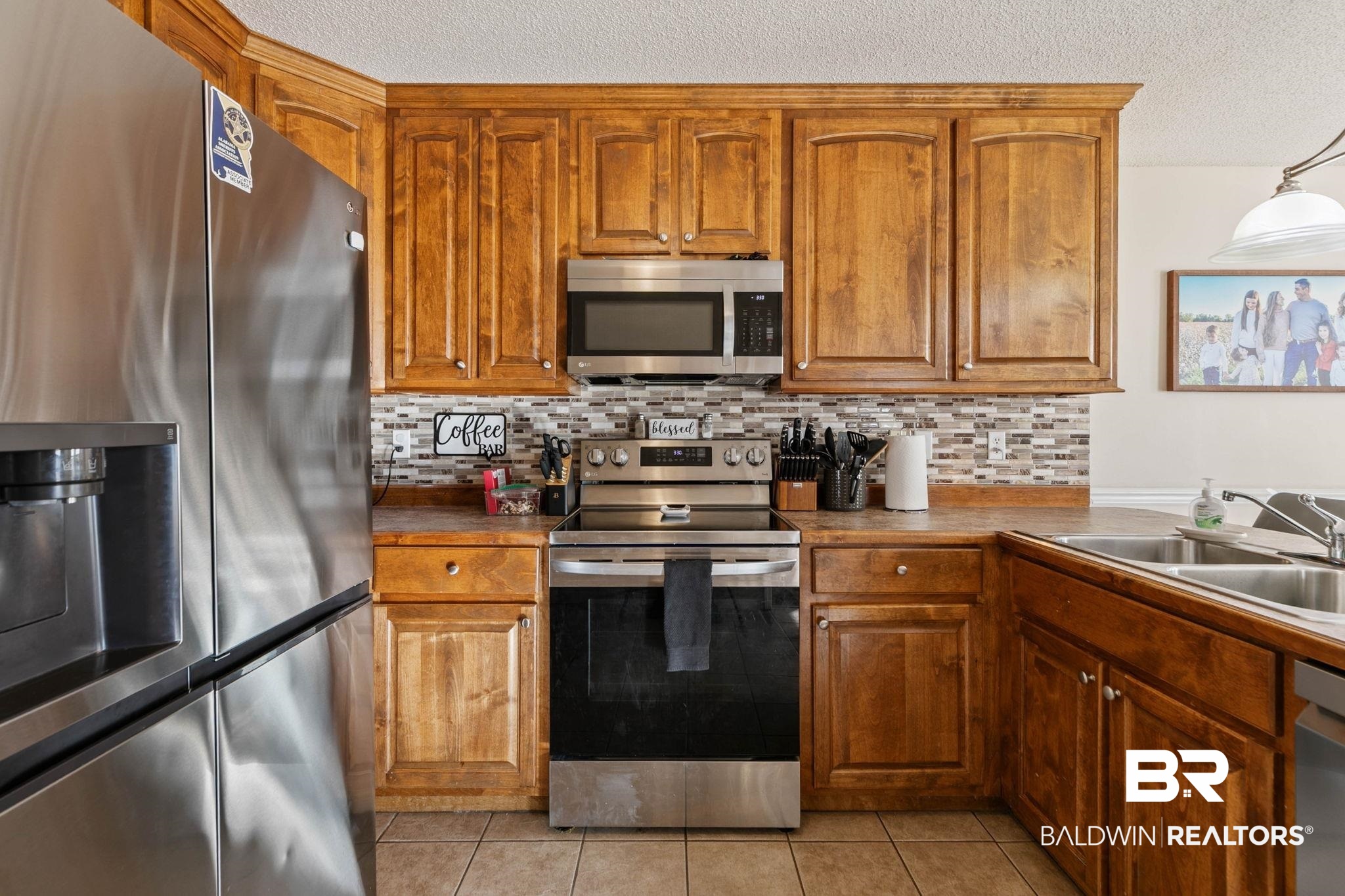 55750 Lottie Road Perdido, AL 36562 - Photo 64 of 84 Kitchen featuring stainless steel appliances, wood finish cabinetry, a textured ceiling, hanging light fixtures, and tasteful backsplash