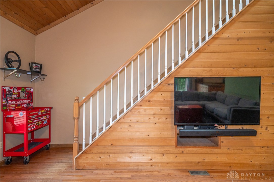 10584 New Biddinger Road Harrison, OH 45030 - Photo 18 of 61 This living area features a grand staircase and warm wood paneling, creating an inviting atmosphere.
