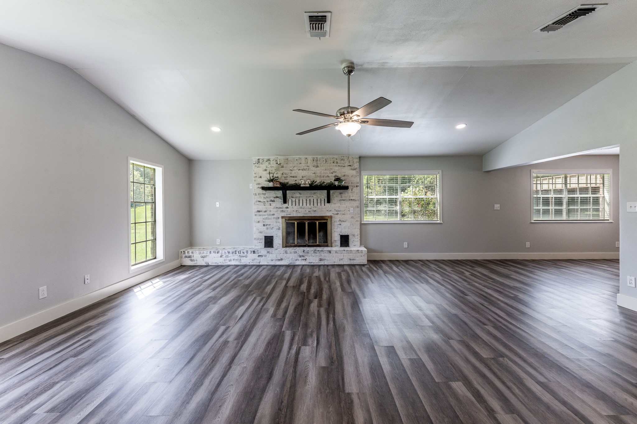 92 Mt Zion Road New Waverly, TX 77358 - Photo 5 of 33 an empty room with wooden floor fireplace and windows
