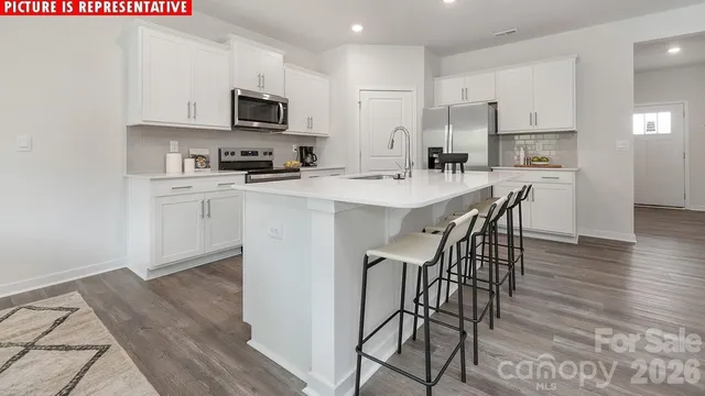 a kitchen with stainless steel appliances a microwave a stove a sink a stove a dining table and chairs