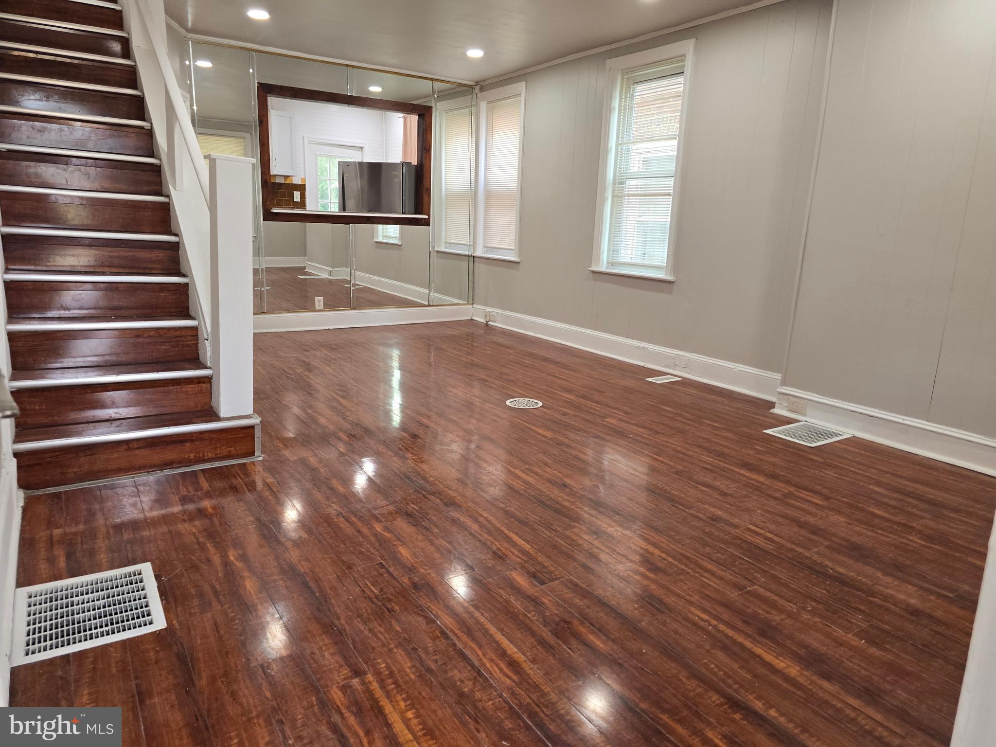 a view of an empty room with wooden floor and windows