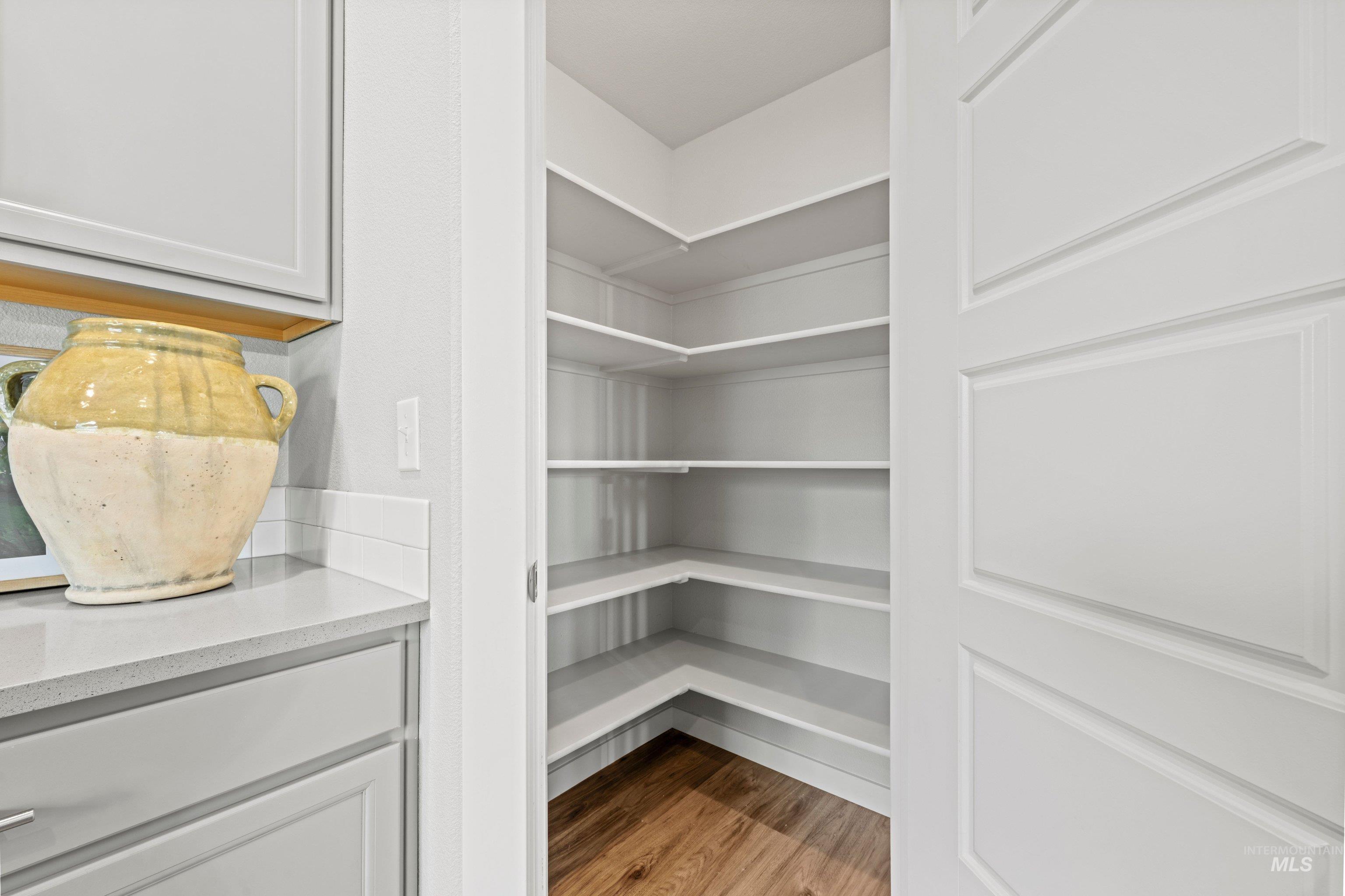 12744 West Fig Street Boise, ID 83713 - Photo 19 of 34 Corner pantry featuring multiple white shelves and wood-finish flooring