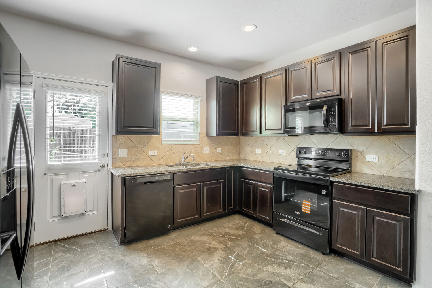 2420 Ranger Pass Seguin, TX 78155 - Photo 8 of 28 Kitchen featuring dark wood cabinetry, granite-style countertops, and a tile backsplash