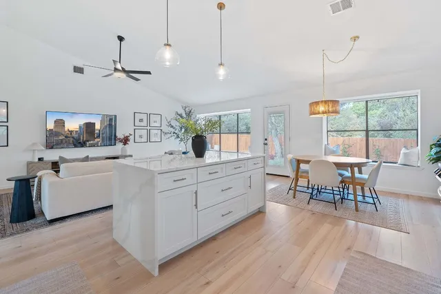 a kitchen with stainless steel appliances granite countertop a stove top oven a sink dishwasher a dining table and chairs with wooden floor