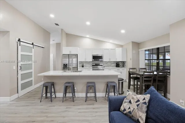 a kitchen with a dining table chairs stove and white cabinets