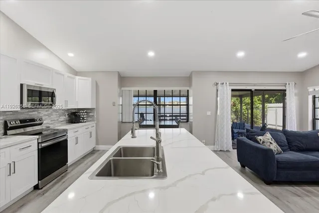 a living room with stainless steel appliances furniture a rug and a view of kitchen
