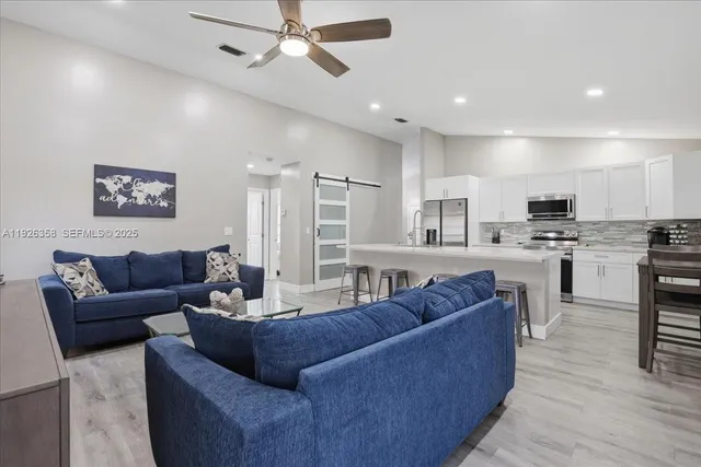 a living room with furniture kitchen and a wooden floor