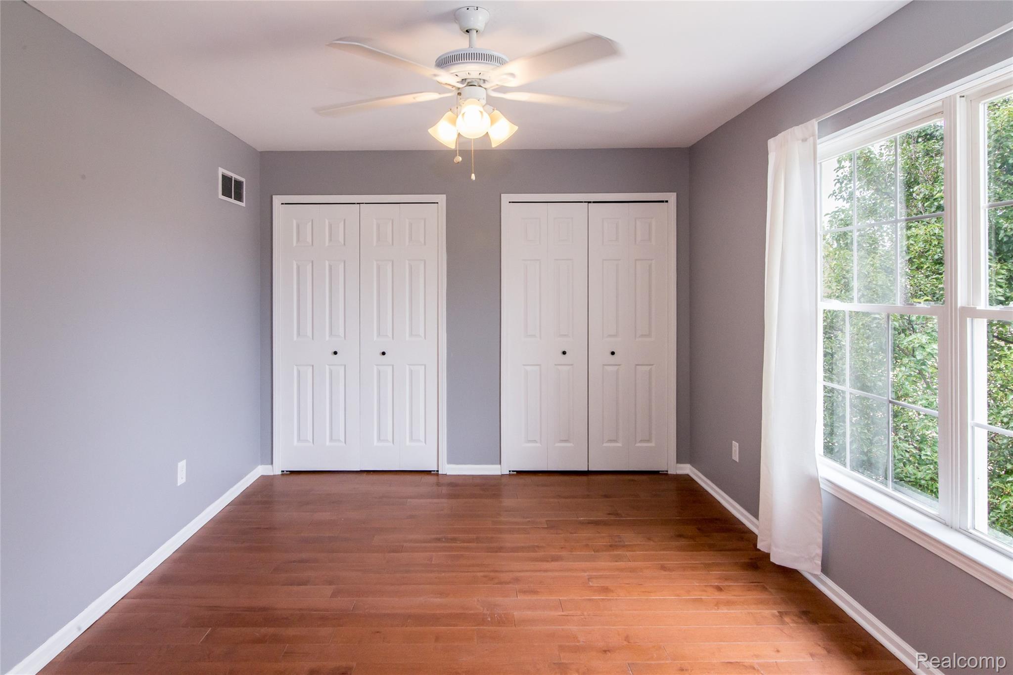 486 Sweet Briar Ridge Linden, MI 48451 - Photo 53 of 69 Hardwood-finish flooring, two sets of bi-fold closet doors, ceiling fan with integrated lighting, and a large window with white trim