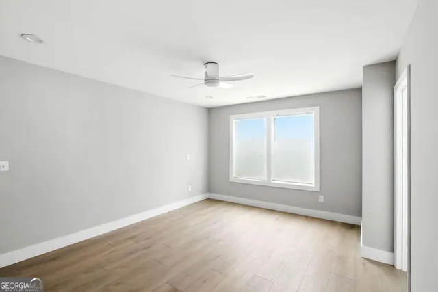 an empty room with wooden floor and ceiling fan