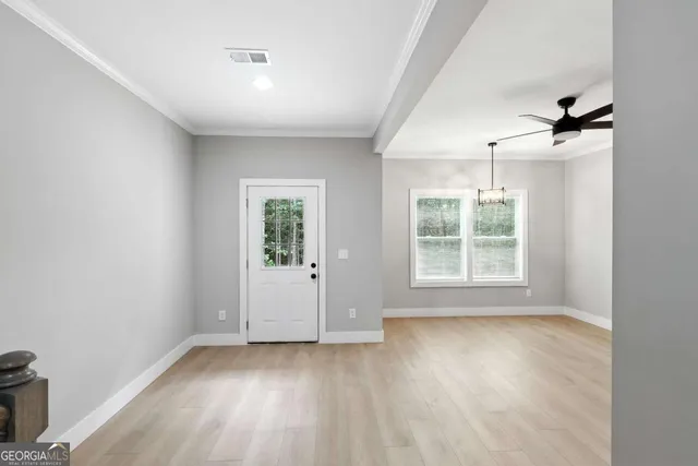 an empty room with wooden floor and windows