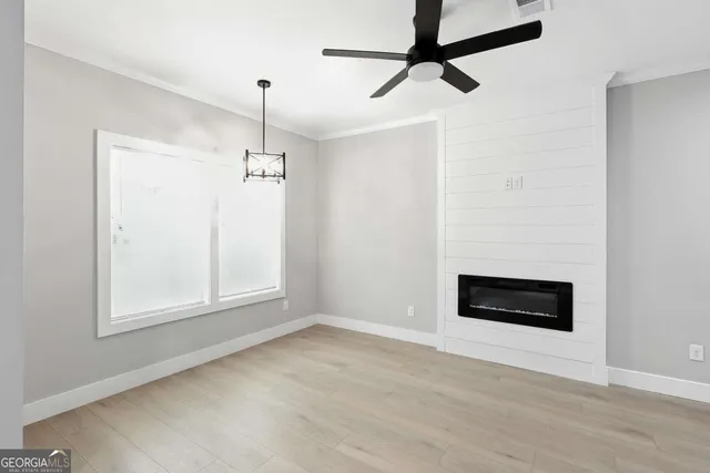 a view of an empty room with a window and kitchen view