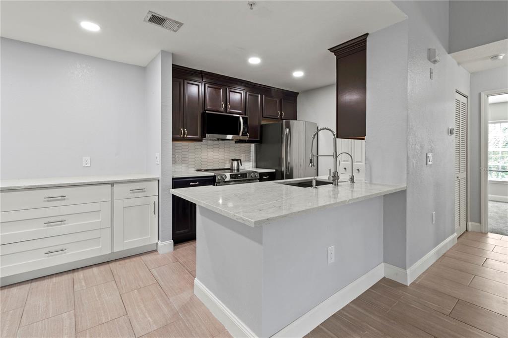 8911 Manor Loop, Unit 204 Lakewood Ranch, FL 34202 - Photo 33 of 45 a kitchen with kitchen island cabinets and stainless steel appliances