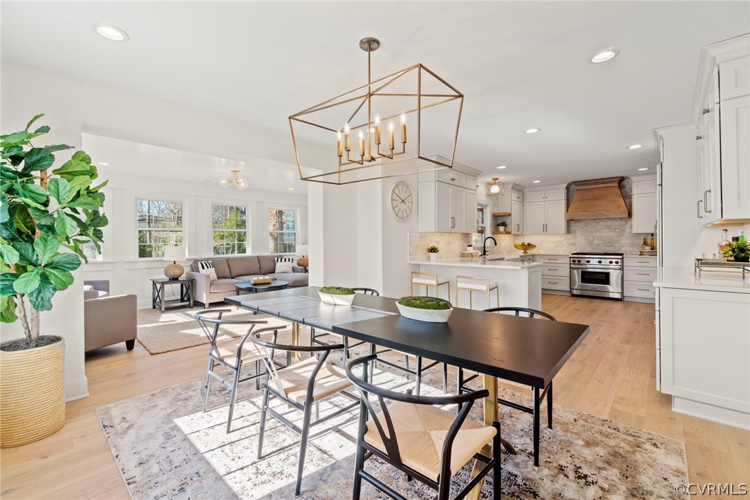 a kitchen with stainless steel appliances kitchen island granite countertop a sink a stove a dining table and chairs with wooden floor