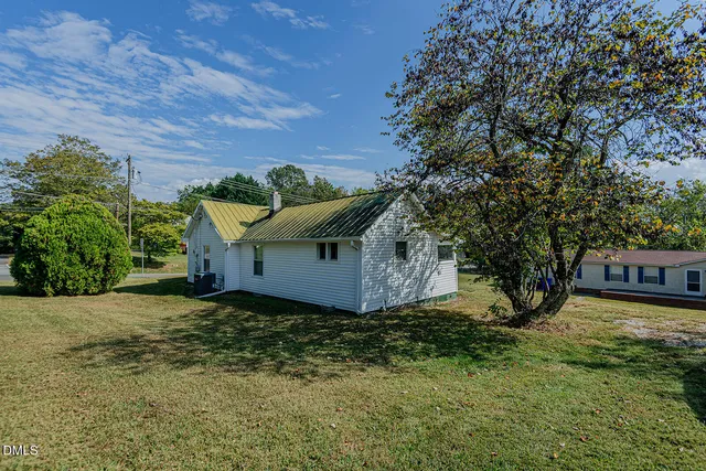 a view of a house with a large tree and a yard in front of it