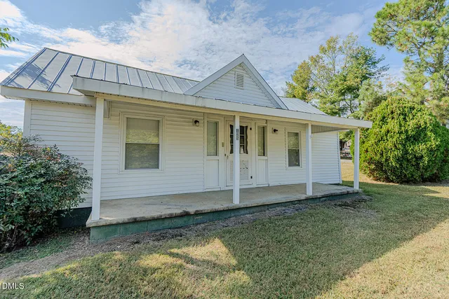 a view of a house with a yard and large trees