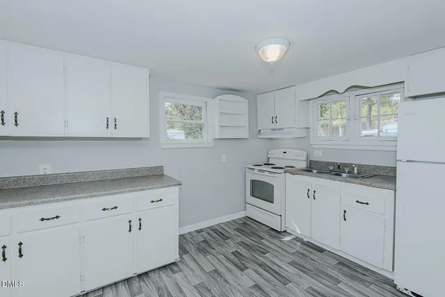a kitchen with granite countertop white cabinets and white appliances