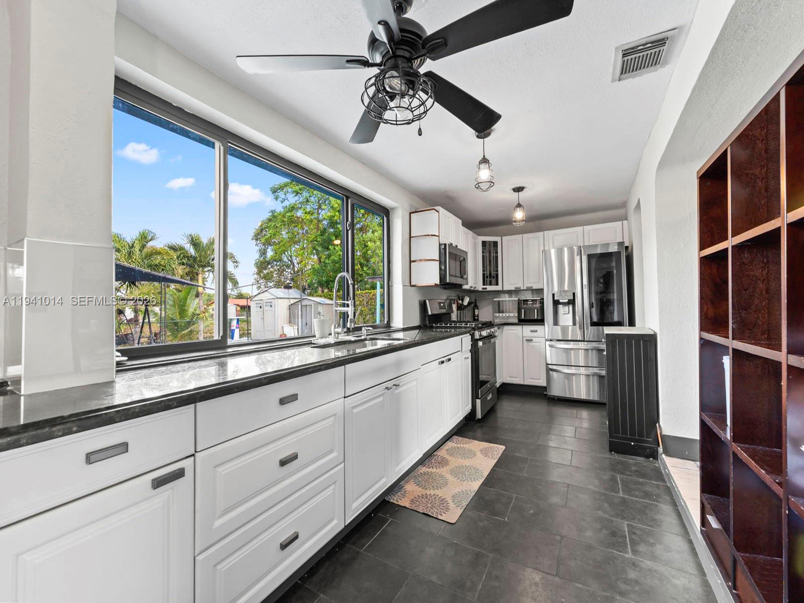 12301 Southwest 28th Street Miami, FL 33175 - Photo 3 of 46 a large kitchen with kitchen island granite countertop a large window cabinets a sink and stainless steel appliances