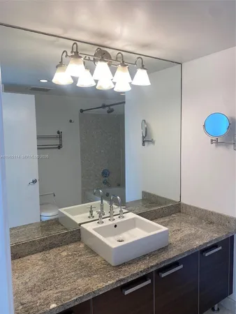 a bathroom with a granite countertop sink and a mirror
