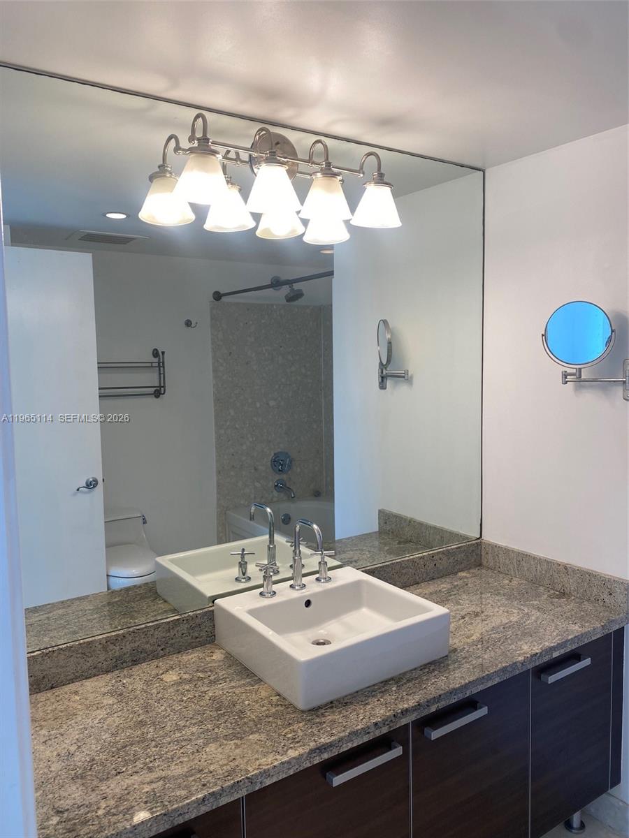 185 Southwest 7th Street, Unit 1705 Miami, FL 33130 - Photo 5 of 7 a bathroom with a granite countertop sink and a mirror