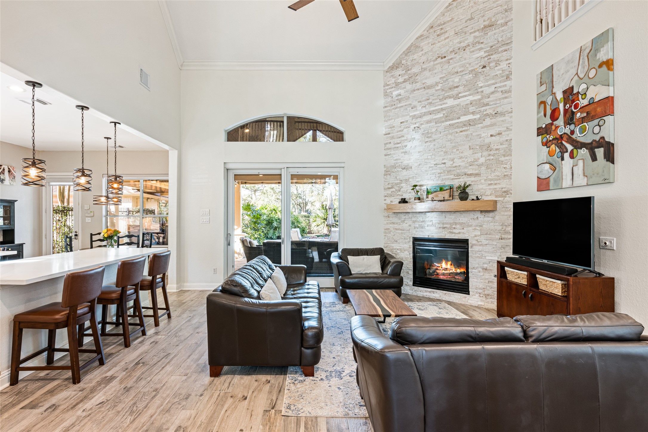 22806 2 Rivers Lane Katy, TX 77450 - Photo 49 of 49 This inviting living area features a high ceiling and an open floor plan, seamlessly connecting to the kitchen. It boasts a cozy fireplace and ample natural light from large glass doors leading to a lush outdoor backyard. Perfect for entertaining and relaxation.