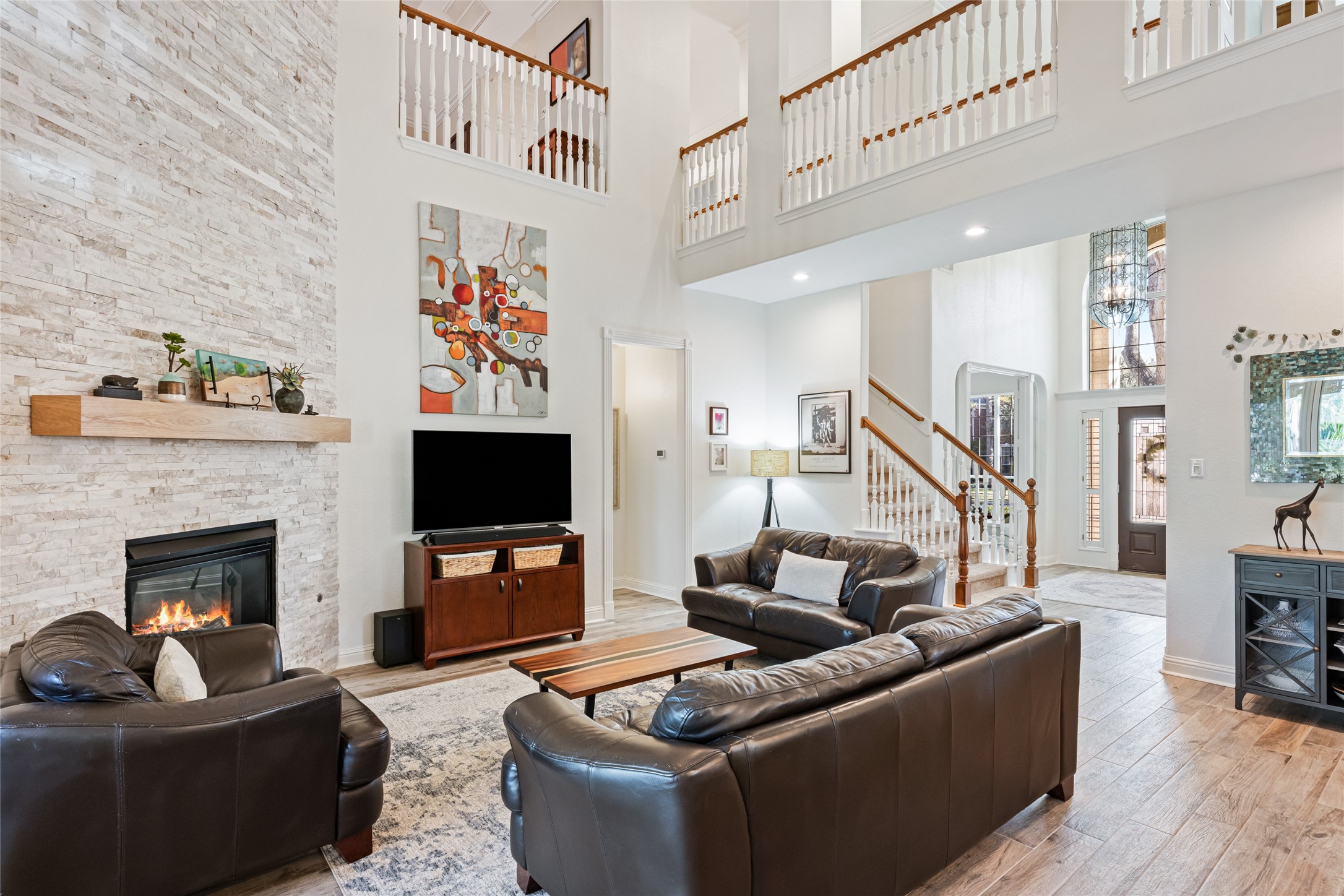 22806 2 Rivers Lane Katy, TX 77450 - Photo 19 of 49 This spacious family room features a striking floor-to-ceiling stone fireplace with custom mantel and gas log fireplace controlled by remote. Soaring ceilings and an upstairs bridge create an open, airy feel while seamlessly connecting the home's living spaces and enhancing the dramatic architectural design.