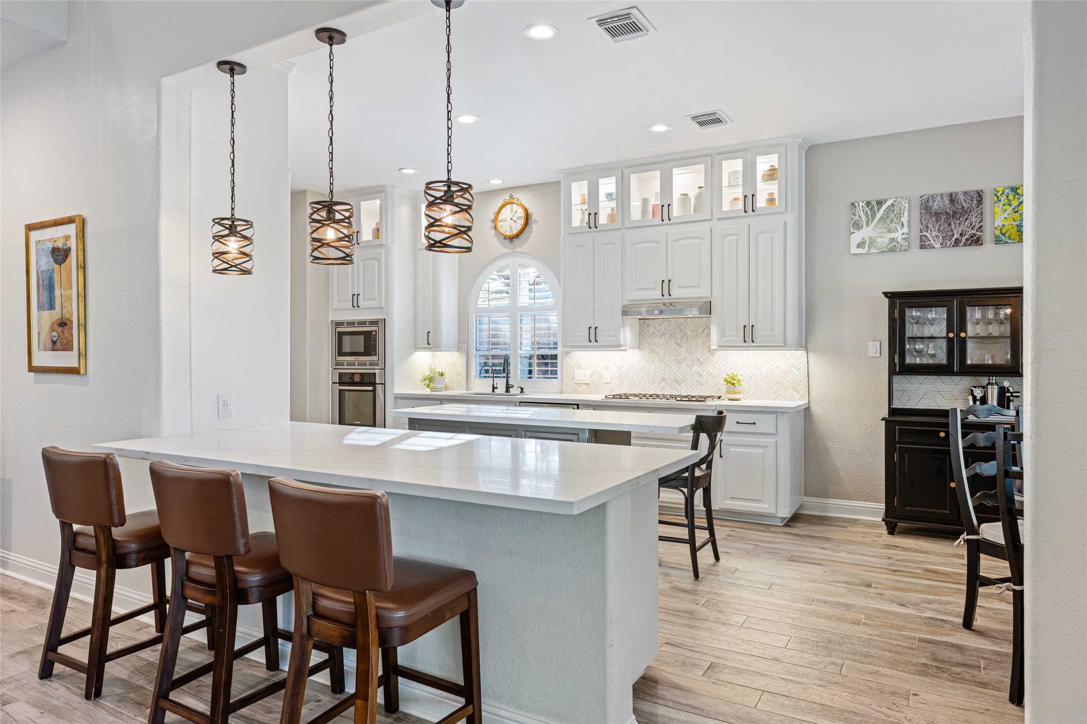 22806 2 Rivers Lane Katy, TX 77450 - Photo 20 of 49 Well-appointed kitchen with a spacious and open layout. Exquisite white quartz countertops with seating for four, pendant lighting, and sleek white cabinetry with under cabinet lighting. The kitchen is equipped with stainless steel appliances and has a cozy breakfast room area. The space is bright and inviting, perfect for entertaining.