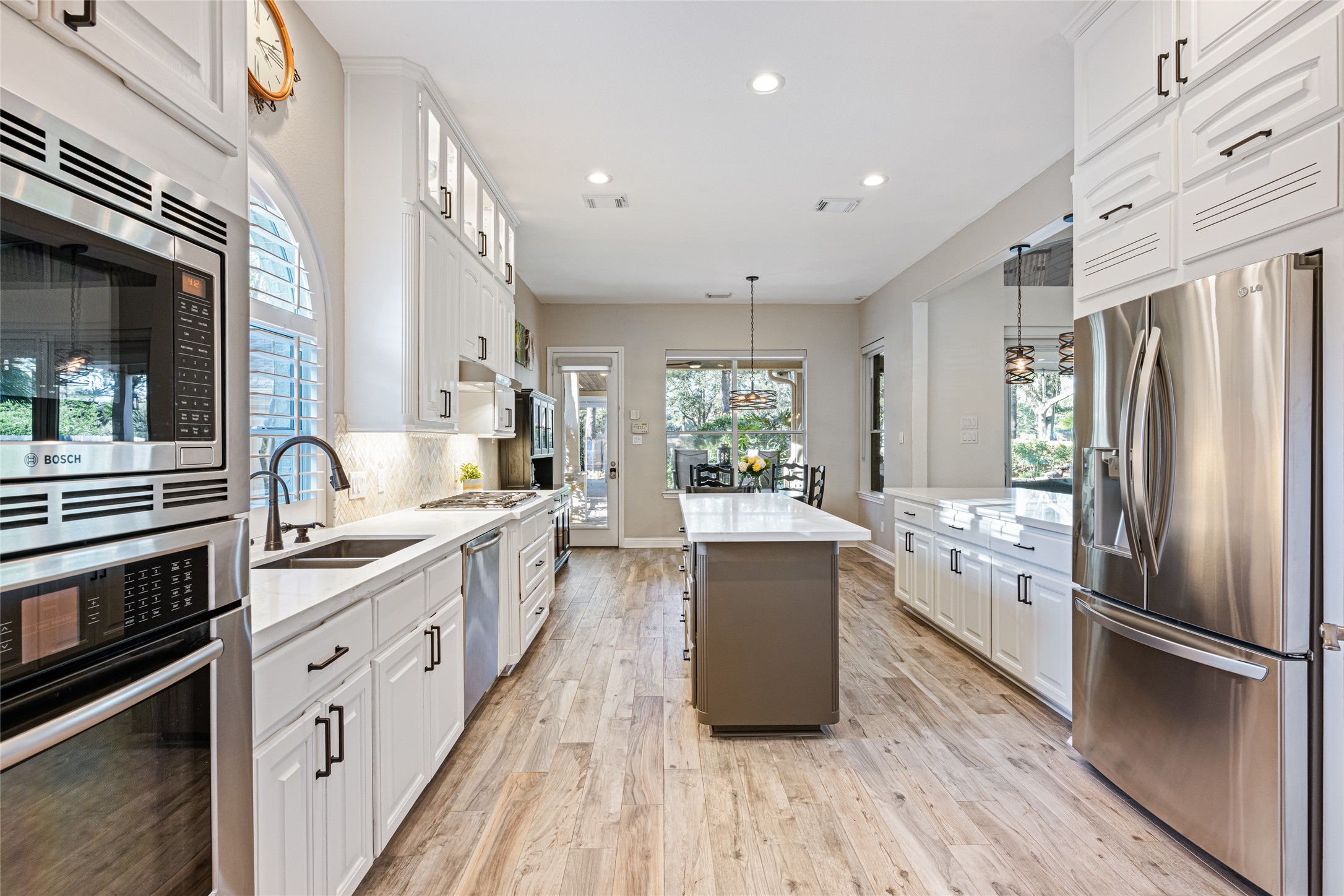 22806 2 Rivers Lane Katy, TX 77450 - Photo 24 of 49 This kitchen features a bright, open layout with white cabinetry, stainless steel appliances, and a central island. It has ample countertop space, modern fixtures, and large windows offering plenty of natural light. The design is both functional and stylish, ideal for cooking and entertaining.