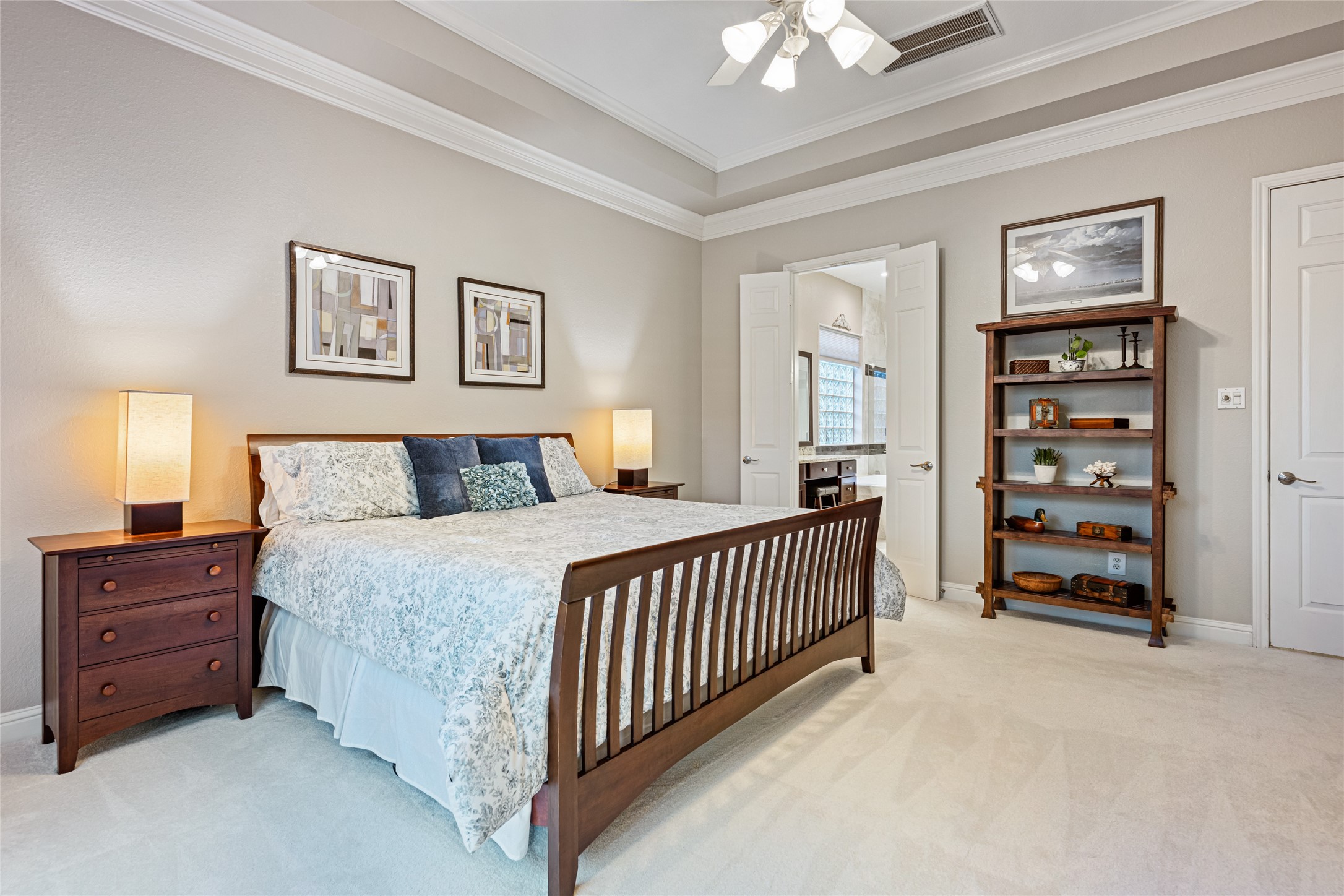 22806 2 Rivers Lane Katy, TX 77450 - Photo 28 of 49 This spacious primary bedroom features soft neutral tones and plush carpeting, creating a cozy atmosphere. French doors lead directly into the private primary bath, offering a seamless and luxurious suite-style layout.
