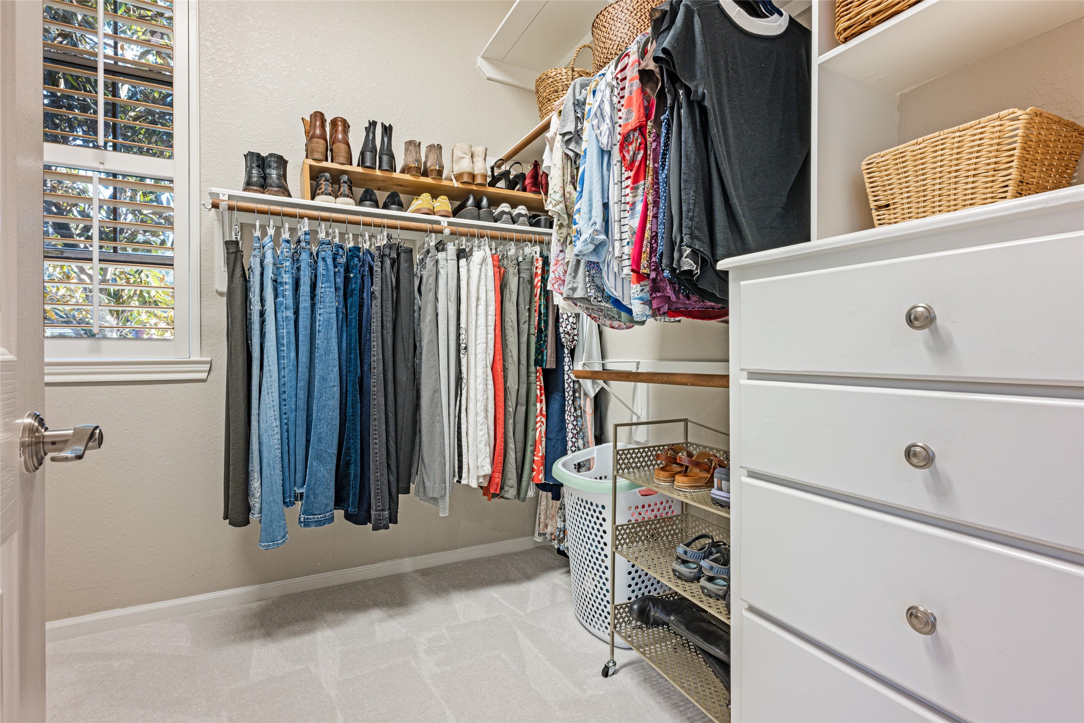 22806 2 Rivers Lane Katy, TX 77450 - Photo 33 of 49 This photo showcases a spacious, well-organized walk-in closet with ample hanging space, shelving, and drawers. Natural light streams in through the window, enhancing the bright, airy feel. Perfect for efficient storage and ease of access.