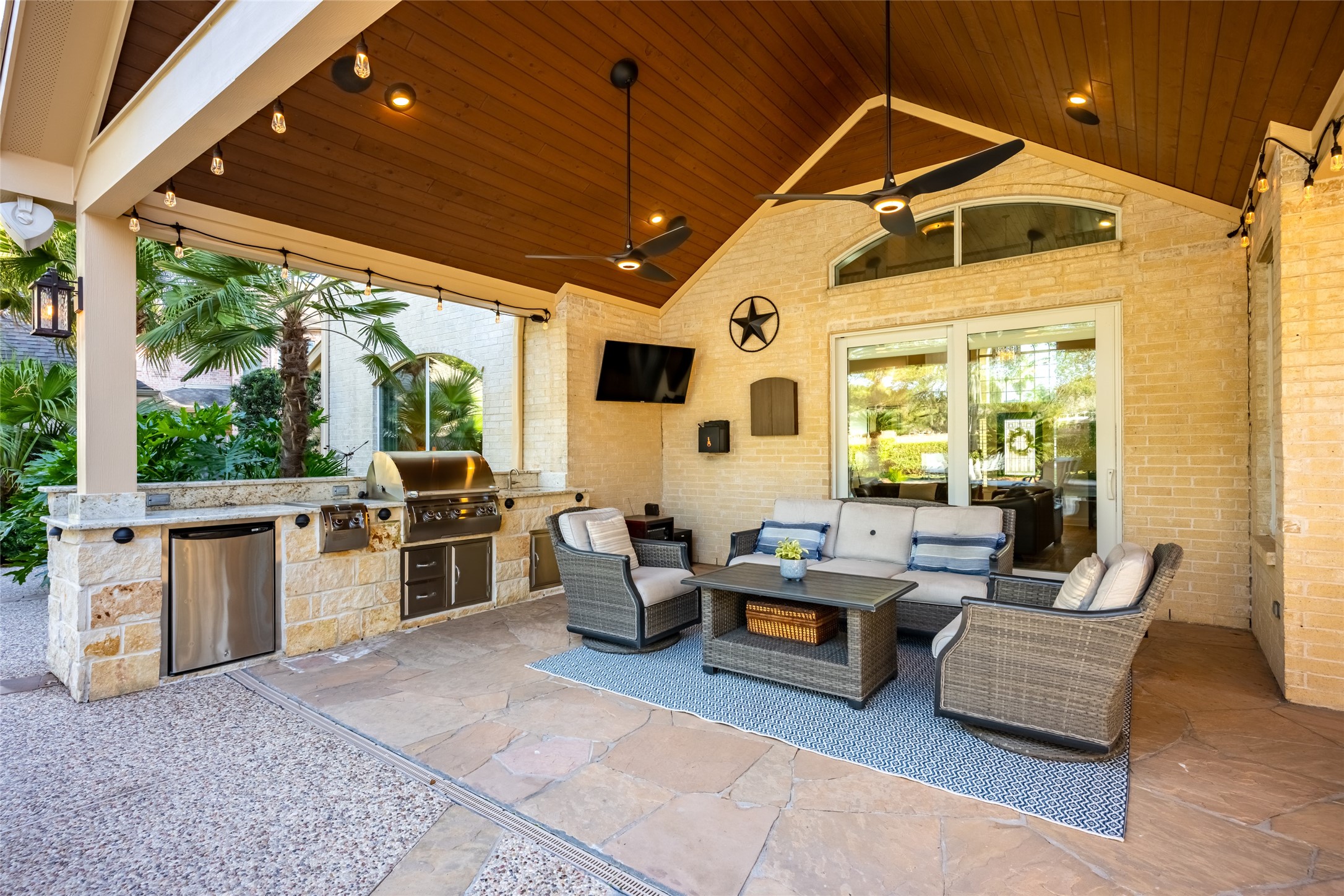 22806 2 Rivers Lane Katy, TX 77450 - Photo 39 of 49 Step outside to your stylish outdoor living area with a vaulted wooden ceiling and ceiling fans, featuring a built-in stone grill and stainless steel appliances.