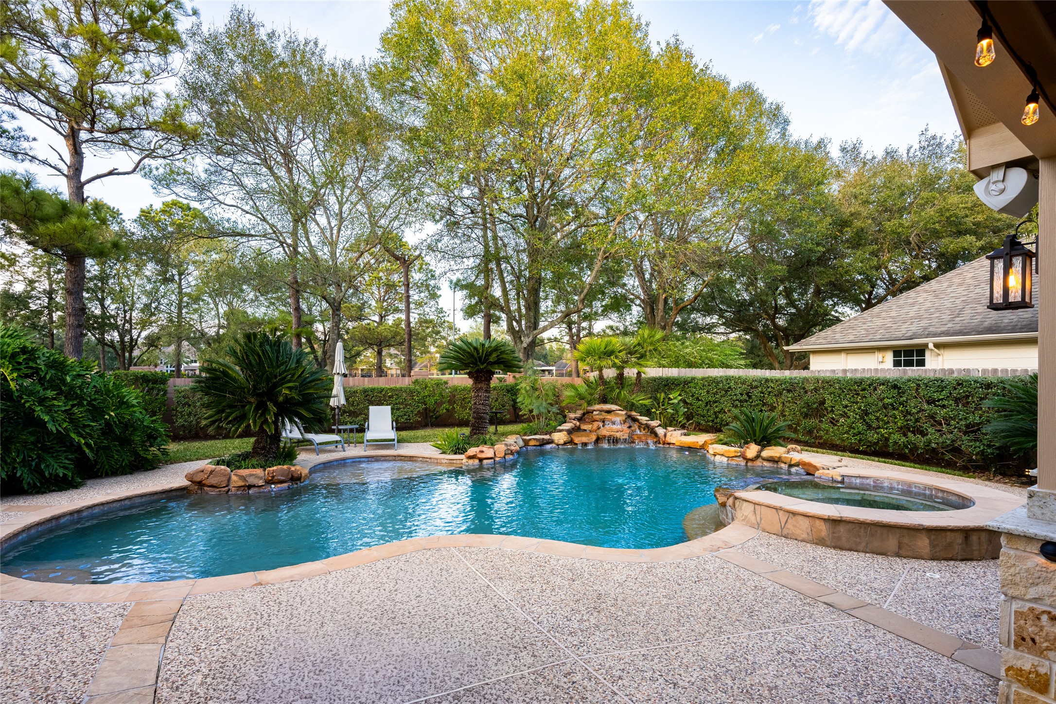 22806 2 Rivers Lane Katy, TX 77450 - Photo 41 of 49 This backyard features a beautifully landscaped pool and spa area, surrounded by lush greenery and mature trees for privacy. A stone waterfall adds a touch of luxury, and the spacious deck offers ample room for relaxation and entertainment.