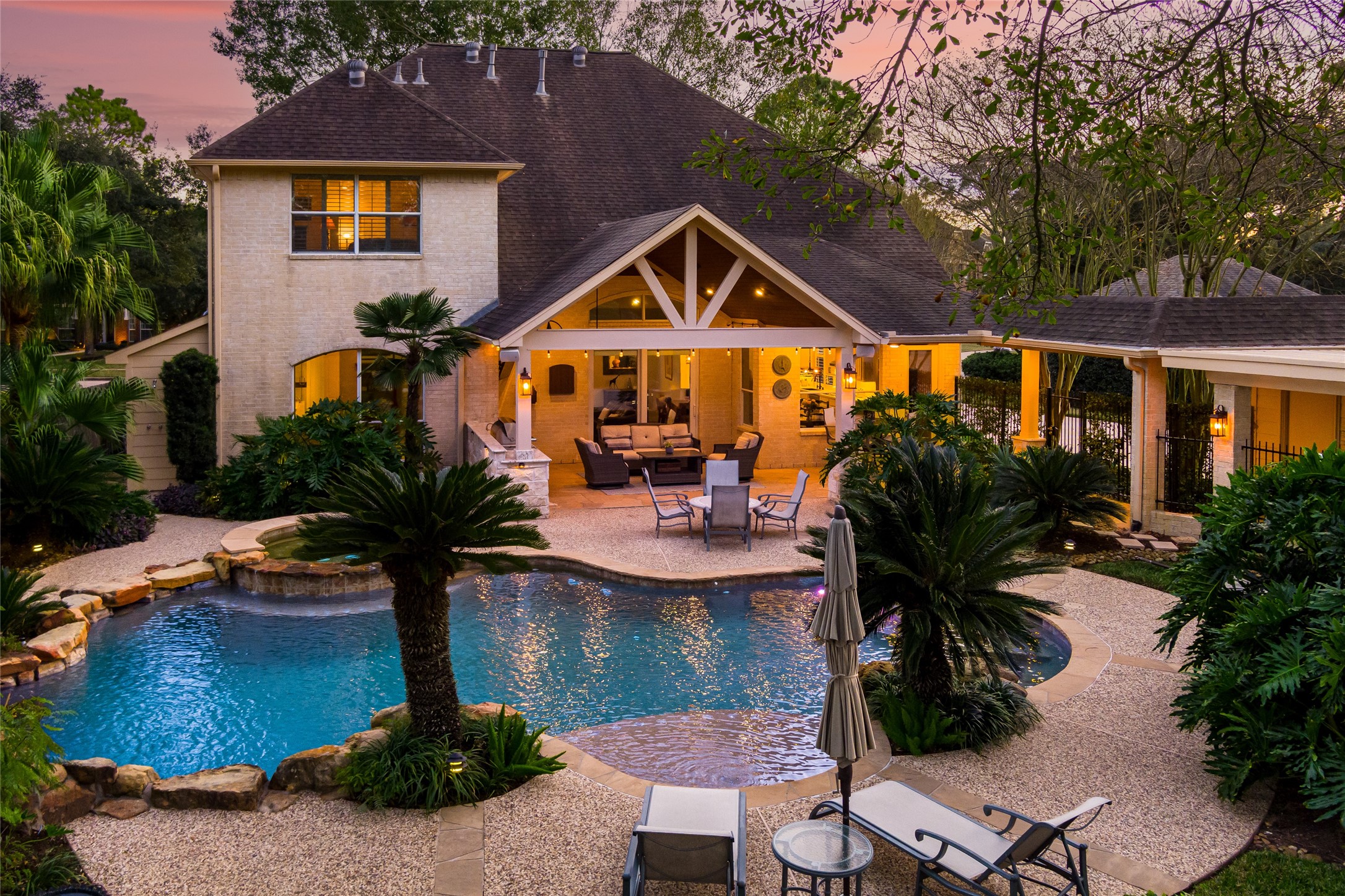 22806 2 Rivers Lane Katy, TX 77450 - Photo 7 of 49 This resort style backyard features a free-form pool and spa, expansive stone patio, and a large covered outdoor living area with ambient lighting. Lush tropical landscaping and mature trees provide privacy and a tranquil setting ideal for entertaining or relaxing year-round. The covered patio offers a cozy outdoor living space, perfect for relaxation or entertaining. Outdoor bathroom with shower for easy pool access.