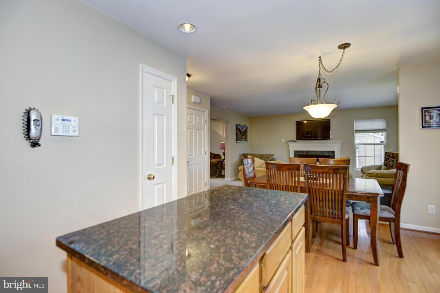 9522 Rommel Drive Columbia, MD 21046 - Photo 5 of 30 a kitchen with stainless steel appliances granite countertop a stove top oven a dining table and chairs with wooden floor