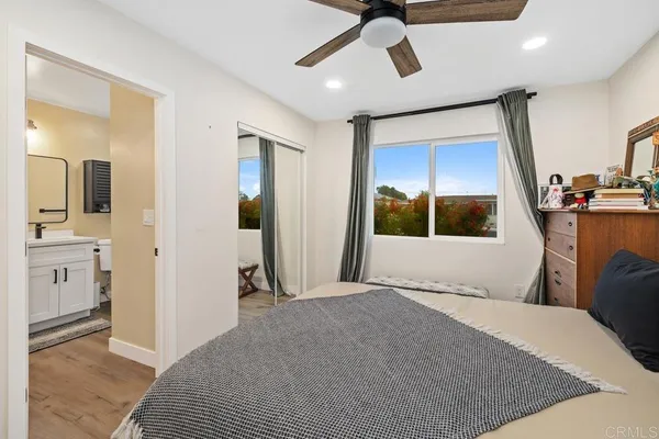 a view of a bedroom with wooden floor and a ceiling fan
