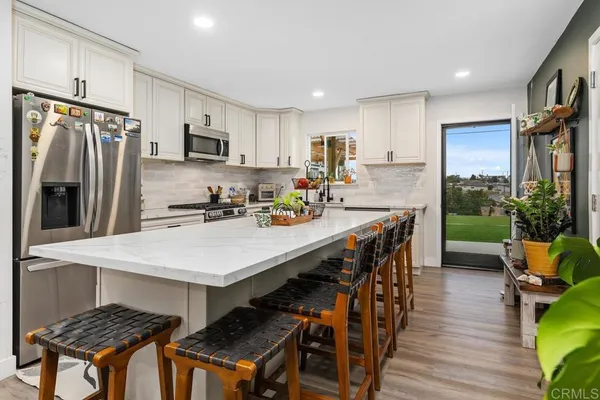 a kitchen with stainless steel appliances granite countertop a table chairs stove and refrigerator