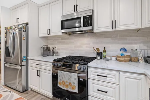 a kitchen with stainless steel appliances granite countertop white cabinets and a stove a oven with white countertops