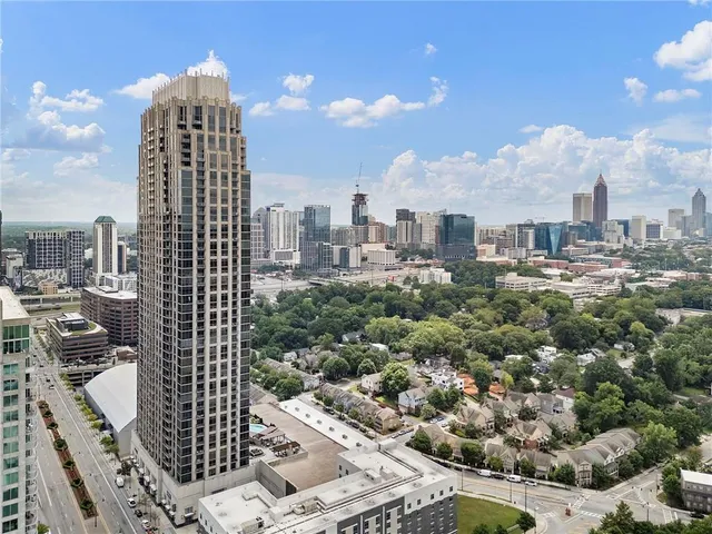 a view of a patio with a table and chairs under an umbrella with a barbeque grill and plants