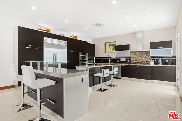 a kitchen with stainless steel appliances a microwave a stove a sink a dining table and chairs