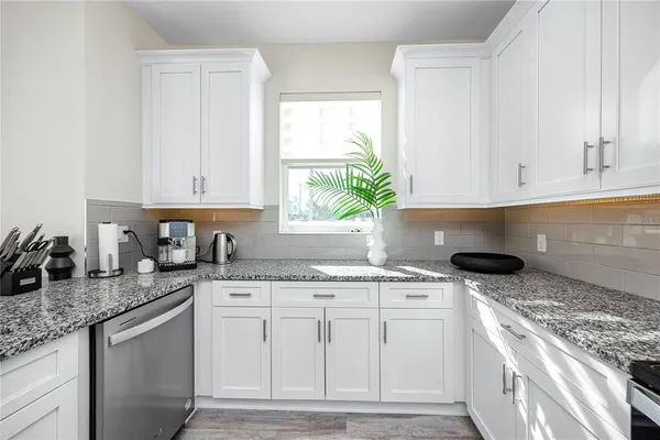 a kitchen with granite countertop a sink stove and cabinets
