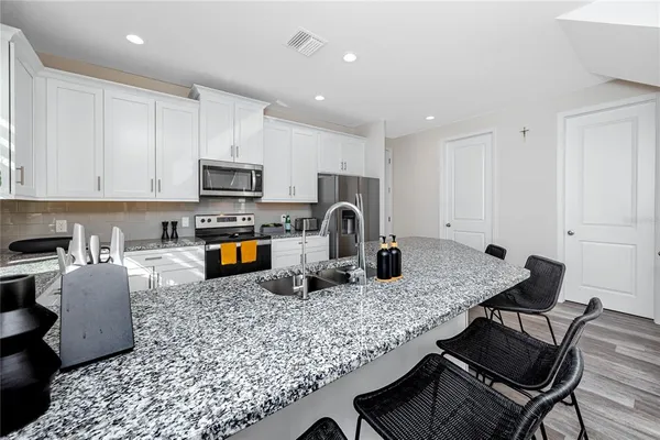 a kitchen with granite countertop a stove a sink a microwave a dining table and chairs
