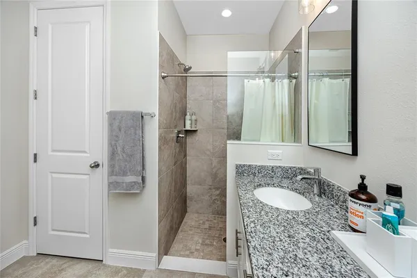 a bathroom with a granite countertop sink a mirror and shower