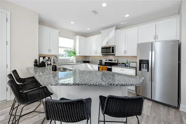 a kitchen with stainless steel appliances granite countertop a stove a refrigerator a sink a stove a dining table and chairs