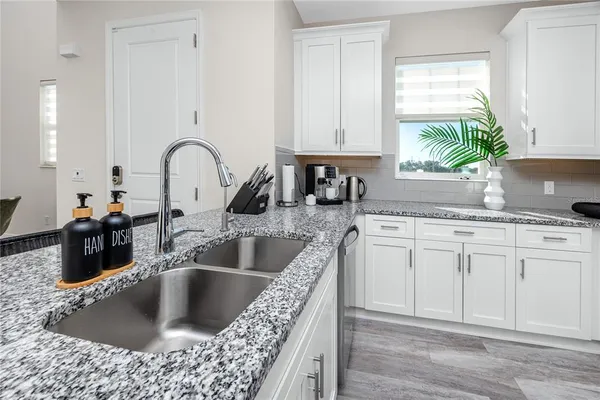 a kitchen with white cabinets a sink and dishwasher