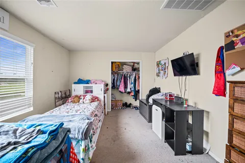 a bedroom with a bed a flat screen tv and a window
